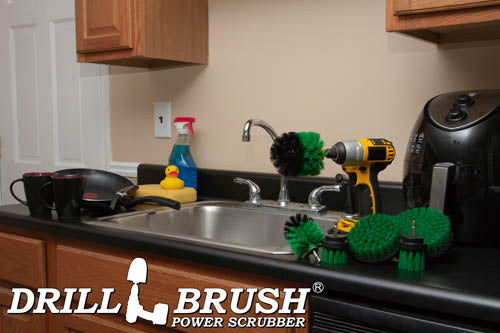 The Drillbrush 542OMS-2L Medium Green Kitchen Brush Kit in a cordless drill sitting on a kitchen counter in front of a sink, coffeemaker, and dishes.