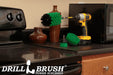 The Drillbrush 42J-5X Medium Green Kitchen Brush Kit in a cordless drill sitting on a counter next to a stove in front of a microwave and decorative vases.