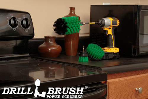 The Drillbrush 42J-5X Medium Green Kitchen Brush Kit in a cordless drill sitting on a counter next to a stove in front of a microwave and decorative vases.