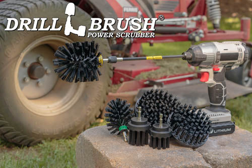 The Drillbrush 542OMS-2L-7X Ultra Stiff Black Grill & Industrial Brush Kit in a cordless drill sitting on stone bricks in front of a ride-on lawnmower.