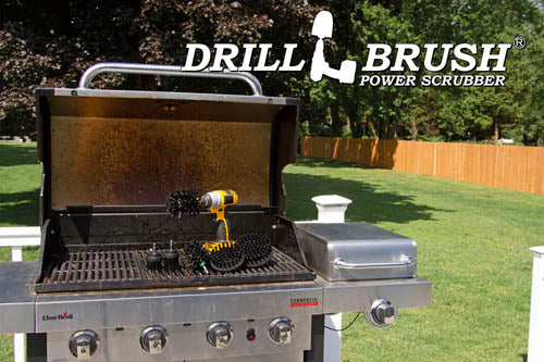 The Drillbrush 542OMS-2L Ultra Stiff Black Grill & Industrial Brush Kit in a cordless drill sitting on an open grill in front of a grassy backyard.