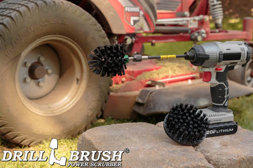 The Drillbrush 4M-5X Ultra Stiff Black Brush Kit in a cordless drill sitting on stone bricks in front of a ride-on lawnmower.