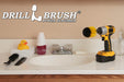 Drillbrush Mini Medium Yellow Bathroom Brush in a cordless drill on a bathroom counter in front of a sink and some toiletries.