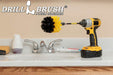 Drillbrush Original Medium Yellow Bathroom Brush in a 5 inch extension in a cordless drill on a bathroom counter in front of a sink and some toiletries.