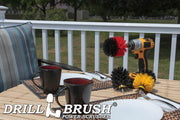 The Drillbrush Medium Yellow, Stiff Red and Ultra Stiff Black Original 3-piece Variety Brush Kit on deck table set with paper plates, mugs, and silverware in front of a backyard.