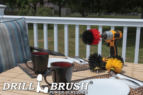 The Drillbrush Medium Yellow, Stiff Red and Ultra Stiff Black Original 3-piece Variety Brush Kit on deck table set with paper plates, mugs, and silverware in front of a backyard.