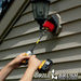 Drillbrush Original Stiff Red Outdoor & Patio Brush in a 7 inch extension cleaning a high-up outdoor lamp.
