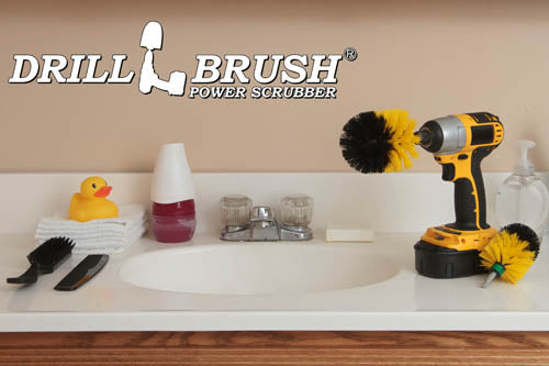The Drillbrush MO Medium Yellow Bathroom Brush Kit in a cordless drill sitting on a bathroom counter next to a sink and toiletries.