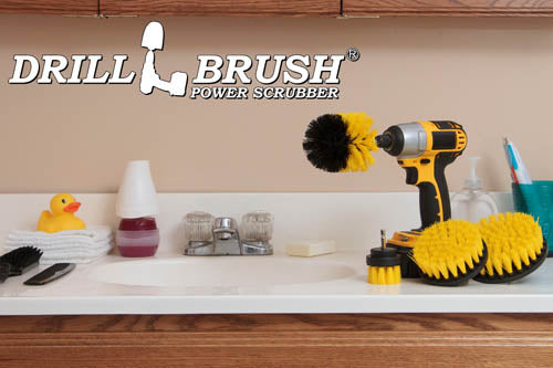 The Drillbrush 542O Medium Yellow Bathroom Brush Kit in a cordless drill sitting on a bathroom counter next to a sink and toiletries.