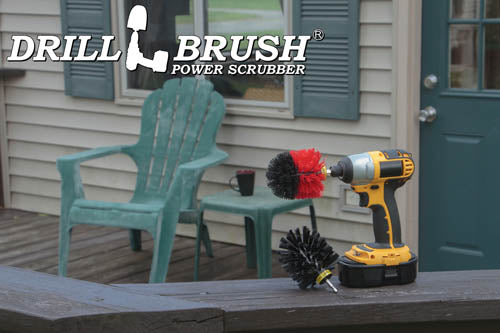 The Drillbrush Red Stiff and Ultra Stiff black 2-piece Variety Brush Kit in a cordless drill sitting on a deck railing in front of vinyl furniture.