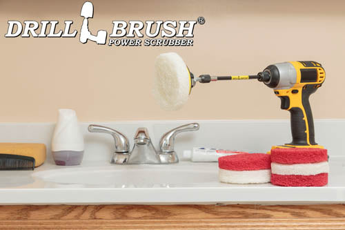 The Drillbrush 3 Soft White & 3 Moderate Red 4 inch Scrubbing Pads and 5 inch extension Kit, with one pad on a 3 inch backer attached to an extension in a cordless drill on a bathroom counter in front of a sink.
