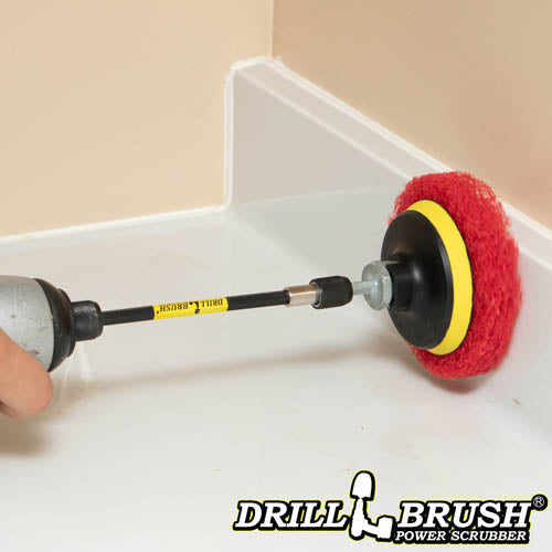 The Drillbrush Moderate Red 4 inch Scrubbing Pads on a 3 inch backer attached to an extension in a cordless drill cleaning the backsplash on a bathroom counter.