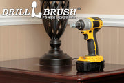 The Drillbrush Threaded 5/8in-11 threads-per-inch bolt to 1/4in Quickchange Adpater in a cordless drill on a wooden end table in front of a lamp.