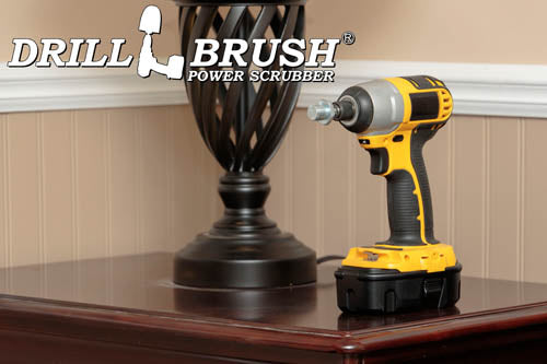 The Drillbrush Threaded 5/8in-11 threads-per-inch bolt to 1/4in Quickchange Adpater in a cordless drill on a wooden end table in front of a lamp.
