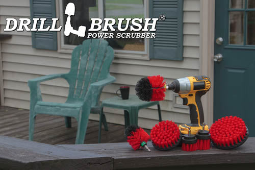 The Drillbrush 542OMS-2L Red Stiff Outdoor & Patio Brush Kit in a cordless drill sitting on a deck railing in front of vinyl furniture.