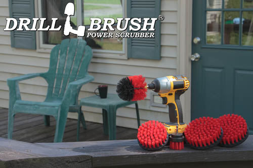 The Drillbrush 5542O Red Stiff Outdoor & Patio Brush Kit in a cordless drill sitting on deck railing in front of vinyl furniture.