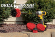 The Drillbrush 542O-7X Red Stiff Outdoor & Patio Brush Kit in a cordless drill sitting on a stone brick planter in front of two shrubs.