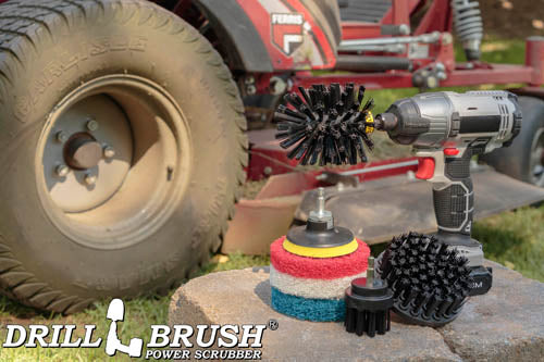 The Ultra Stiff Black Drillbrush 42O Grill & Industrial Kit with three 4 inch Variety Pads with an Original in a cordless drill on a concrete block in front of a ride on lawnmower.