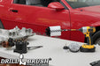 The Drillbrush 42J-5X Soft White Home & Auto Brush Kit in a cordless drill sitting on a table in front of a red sports car.