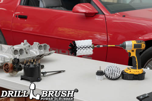 The Drillbrush 42J-5X Soft White Home & Auto Brush Kit in a cordless drill sitting on a table in front of a red sports car.