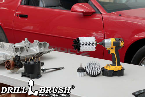 The Drillbrush 42J Soft White Home & Auto Brush Kit in a cordless drill sitting on a table in front of a red sports car.