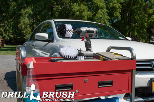 The Drillbrush 52O Soft White Home & Auto Brush Kit in a cordless drill sitting on a tool cart in front of a white sedan.