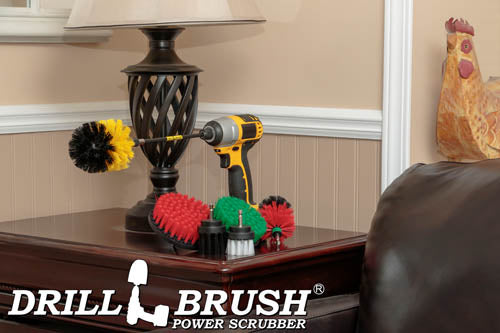 The Drillbrush 542OMS-2L-7X Variety Brush Kit in a cordless drill sitting on a wooden end table next to a leather sofa in front of a lamp.