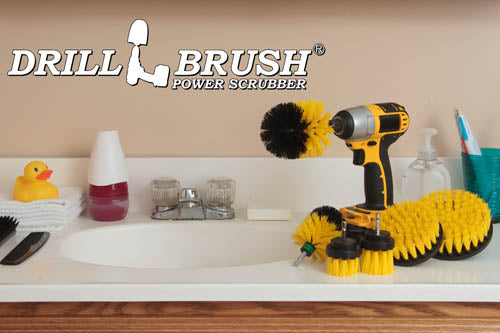 The Drillbrush 542OMS-2L Medium Yellow Bathroom Brush Kit in a cordless drill sitting on a bathroom counter next to a sink and toiletries.
