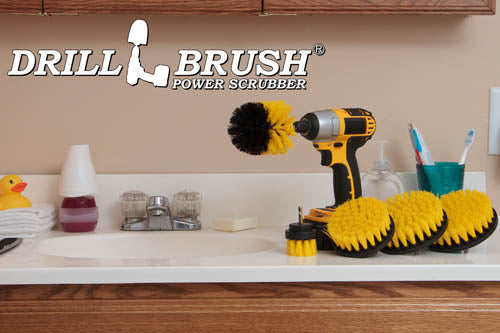 The Drillbrush 5542O Medium Yellow Bathroom Brush Kit in a cordless drill sitting on a bathroom counter next to a sink and toiletries.