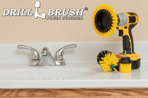 The Drillbrush EMS-2L Medium Yellow Bathroom Brush Kit in a cordless drill sitting on a bathroom counter next to a sink.