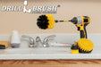 The Drillbrush 42O-5X Medium Yellow Bathroom Brush Kit in a cordless drill sitting on a bathroom counter next to a sink and toiletries.