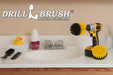 The Drillbrush 4O Medium Yellow Bathroom Brush Kit in a cordless drill sitting on a bathroom counter next to a sink and toiletries.