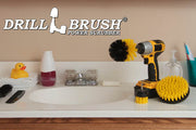 The Drillbrush 52O Medium Yellow Bathroom Brush Kit in a cordless drill sitting on a bathroom counter next to a sink and toiletries.