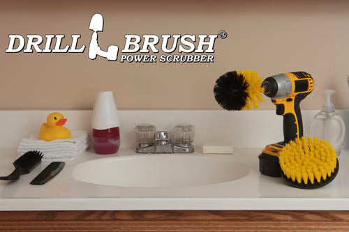 The Drillbrush 5O Medium Yellow Bathroom Brush Kit in a cordless drill sitting on a bathroom counter next to a sink and toiletries.