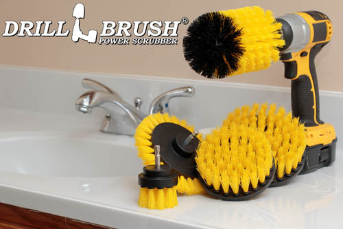 The Drillbrush E542J Medium Yellow Bathroom Brush Kit in a cordless drill sitting on a bathroom counter next to a sink.